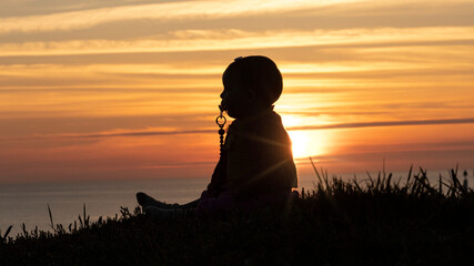 baby girl at sunset in front of the sea