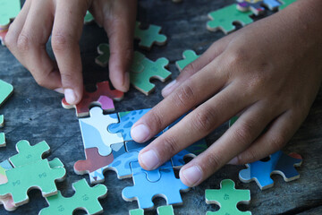 hands playing jigsaw puzzle on wooden table