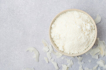 Coconut flakes in a bowl on a light background, horizontal.