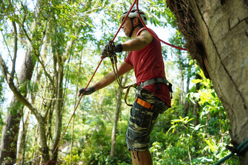 A man is walking across a challenging ropes course in the extreme park