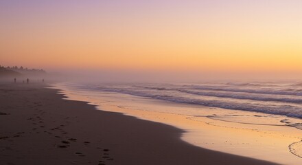 People stroll on beach during a hazy orange sunrise, waves breaking behind them