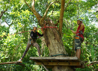 A man and a woman is walking across a challenging ropes course in the extreme park
