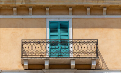 Traditional Italian Architecture with Turquoise Shutters and Ornate Wrought Iron Balcony on...