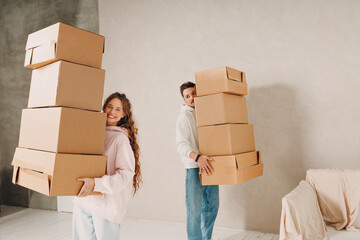 Happy young family couple man and woman moving with cardboard boxes to new estate home apartment.