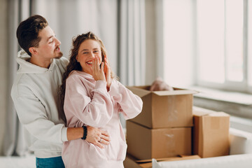 Happy young family couple man and woman hugging after moving cardboard boxes to their new apartment.