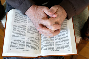 Naklejka premium Man praying to the Bible at home.