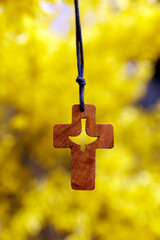 Broom in bloom in spring. Wooden christian coss with Holy Spirit on a yellow background.