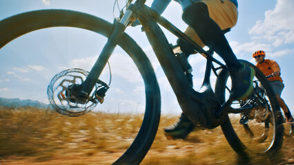 A thrilling close-up shot of two cyclists racing through a field, their bicycles' wheels spinning...