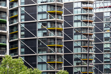 Modern residential facade in London with glass balconies, pattern, and vertical lines, ideal for city living, architecture, and urban development stock.
