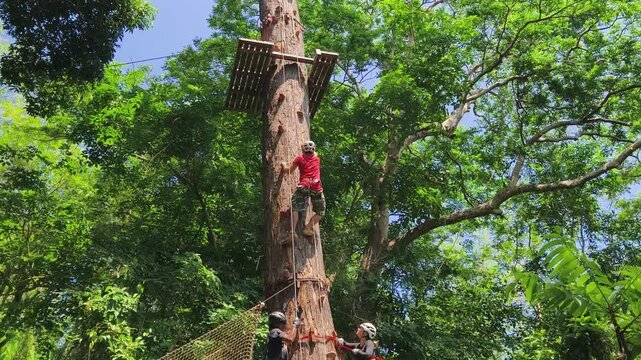 A man and a woman is walking across a challenging ropes course in the extreme park