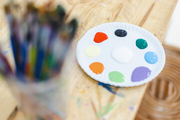 Sustainable and ecofriendly craft setup with painting palette featuring various paint colors and blurred brushes in background inspiring creative art projects