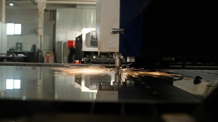 Precision industrial laser cutting machine processing metallic surface with automated robotic movements, creating intricate patterns through advanced manufacturing technology