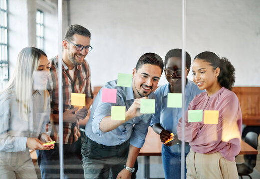 Business people meeting at office and using sticky notes on glass to share idea. Brainstorming and teamwork concept. Sticky note on glass wall.