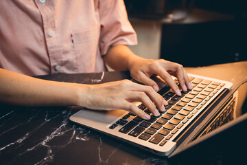 Close-up of Person Typing on Laptop Keyboard in Modern Workspace with Dark Marble Surface