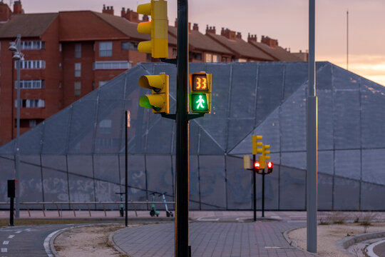 Urban traffic lights with green signals against geometric glass facade, showcasing modern architecture, urban elements and color contrast for design and background use.