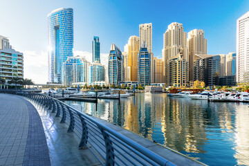  Luxury and comfortable tourism season in UAE. Modern skyscrapers and yachts parked on the pier in Dubai Marina bay.