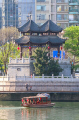 A little wooden Chinese boat beneath the Hejiang Pavilion on the Jinjiang River, a landmark of Chengdu, capital of Sichuan Province and China’s mega park city