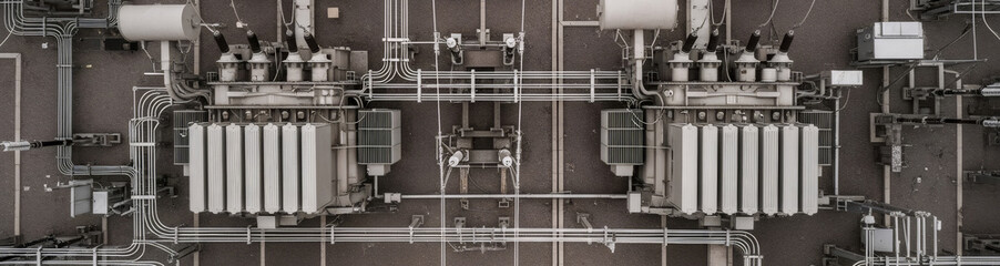 Top down aerial view of a power substation with electrical transformers and cables. Industrial electricity infrastructure concept for energy supply.
