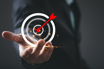 A hand extends towards a target symbol with a dart hitting the center, symbolizing focus, goals,...