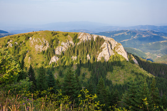 A scenic view of peak in Kopaonik National Park, Serbia, featuring its distinctive white cliffs surrounded by lush green forests and a clear sky.
