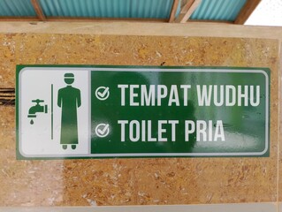 Sign indicating Wudhu washing area and men's toilet in Indonesian language