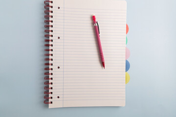 Open blank spiral bound lined notebook and pen