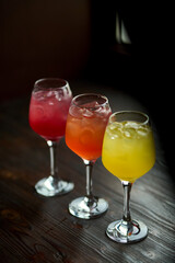 Three colorful cocktails on a wooden table. Alcoholic drinks for party.