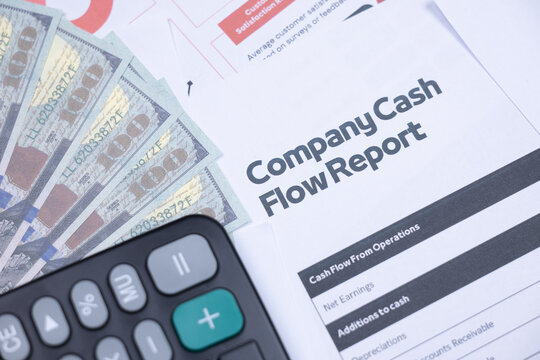 Company cash flow report, US dollar bills, and a calculator symbolize business finance and accounting.