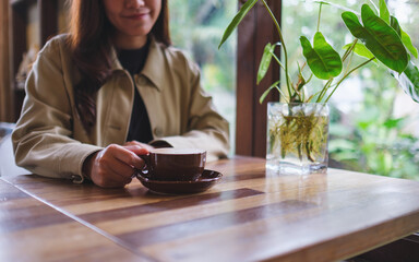 Closeup image of a woman holding a cup of hot coffee in cafe