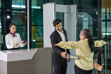 Airline ground staff is using metal scanner for security check every passenger in the airport departure terminal for safety protocol before boarding into plane