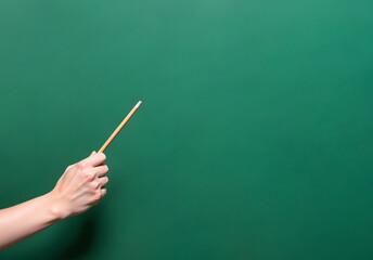 Hand Pointing with Pencil on Green Chalkboard Background. Education Concept