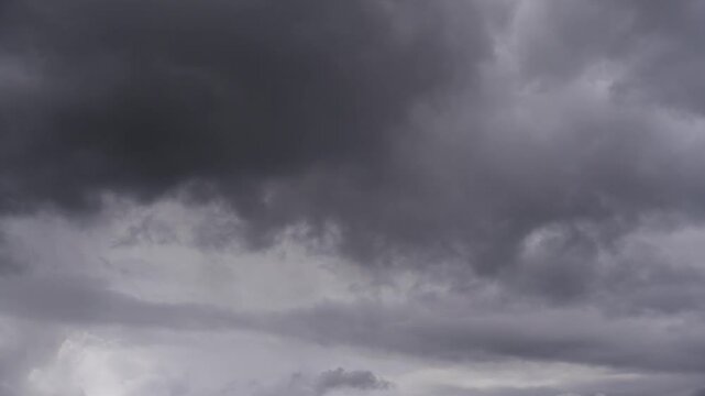 Timelapse of a dramatic sky with dark clouds. Thick dark cloud cover dominates the sky. The scene looks dramatic and foreshadows a storm or rain.