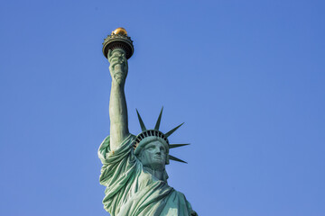 Statue of Liberty in New York City on a clear day. Iconic American symbol captured with bright sky and strong lighting.