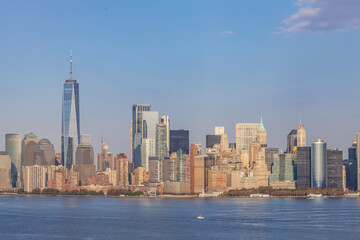 Panoramic view of Lower Manhattan skyline featuring One World Trade Center, seen from across the Hudson River on a clear day in New York City.