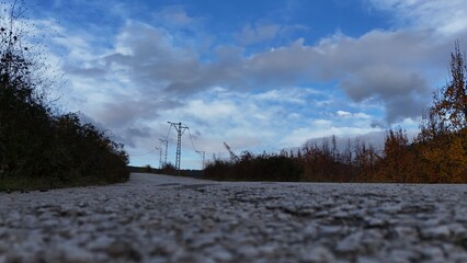 Low-Angle Drone View: A Gravel Road Under a Dynamic Sky with Power Lines in Bursa