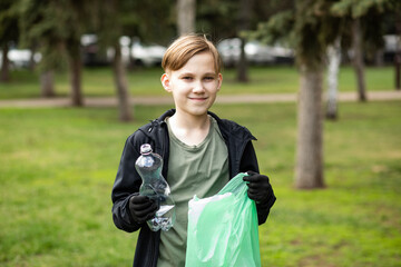 Teenager kid boy picking up trash plastic bottles in the park. Volunteer concept. Ecology,...