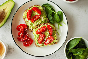 Wholesome healthy breakfast vegan avocado sandwich on wholewheat bread, topped with fresh cherry...