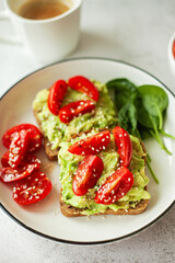 Vegan avocado sandwich, wholewheat bread stacked with creamy avocado and juicy cherry tomatoes and fresh spinach leaves - the perfect bite for a healthy, plant-based lifestyle