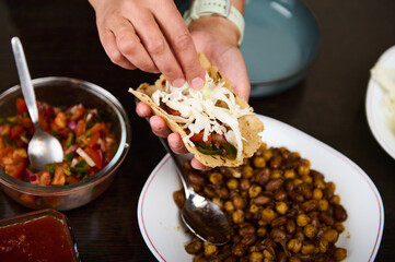 Person Assembling a Fresh Vegetarian Taco with Beans and Salsa