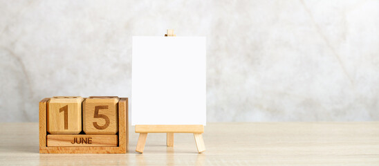 Wooden perpetual calendar showing june 15 and a blank canvas on an easel for your text