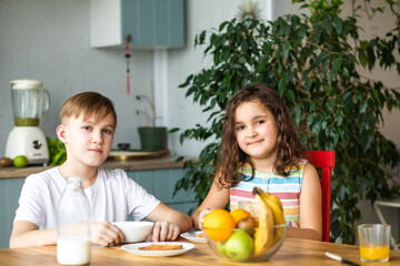 Happy family sister and brother have breakfast with cereal and milk in a kitchen at home