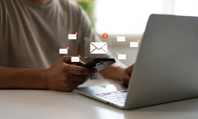 A Businessman using mobile phone, laptop open email with sign reminder for unread emails for notification and taps on a new inbox email notification icon, newsletter. Technology digital online network