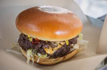 Delicious classic cheeseburger with a juicy beef patty and melted cheese, served on a metal tray. A perfect fast food meal for lunch or dinner.