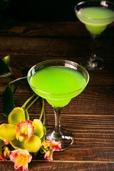Cold green exotic cocktail with decorated flowers orchid and palm leaves. Tropical vibes.