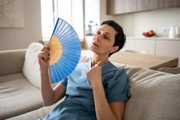 Weary tired stressed woman fanning at home, sweating profusely. No conditioning, oppressive...