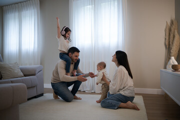 Happy family playing with baby taking first steps at home
