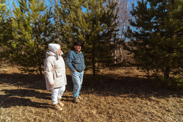 Fototapeta premium Romantic and elderly healthy lifestyle concept. Senior active Caucasian couple holding hands looks happy in park in autumn forest,happy anniversary,happily retired married couple together
