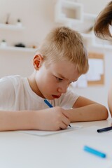 Naklejka premium A loving mother and her son work together on homework at the kitchen table, symbolizing family support, education, and care. The scene highlights the importance of parental guidance