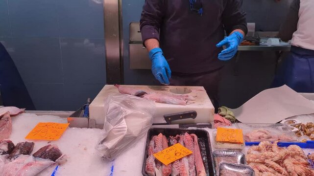 Fresh Fish Preparation at Local Market. This footage showcases the art of filleting fish. Discover the meticulous process behind seafood for consumers in this busy marketplace.