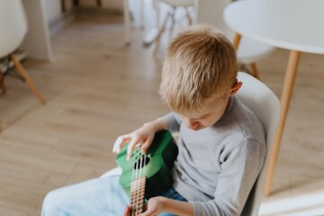Mother and son playing guitar together, family love. The child wears a hearing aid, highlighting...
